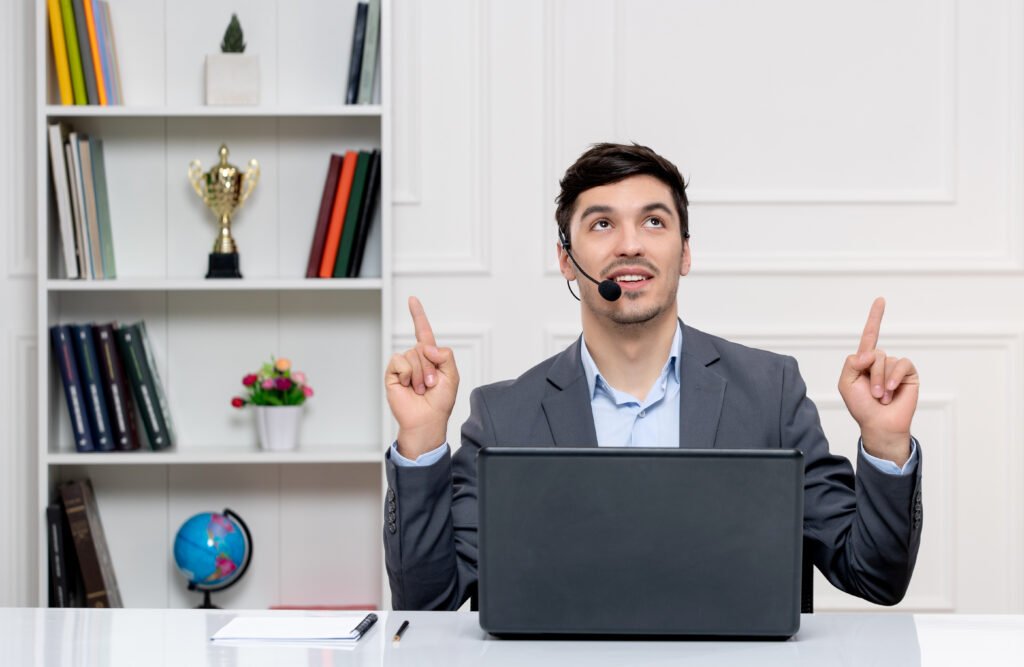 customer-service-handsome-man-grey-suit-with-computer-headset-pointing-up-smiling