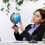 front-view-beautiful-young-businesswoman-black-jacket-blue-shirt-observing-little-globe-front-table-business-job-office_140725-15842